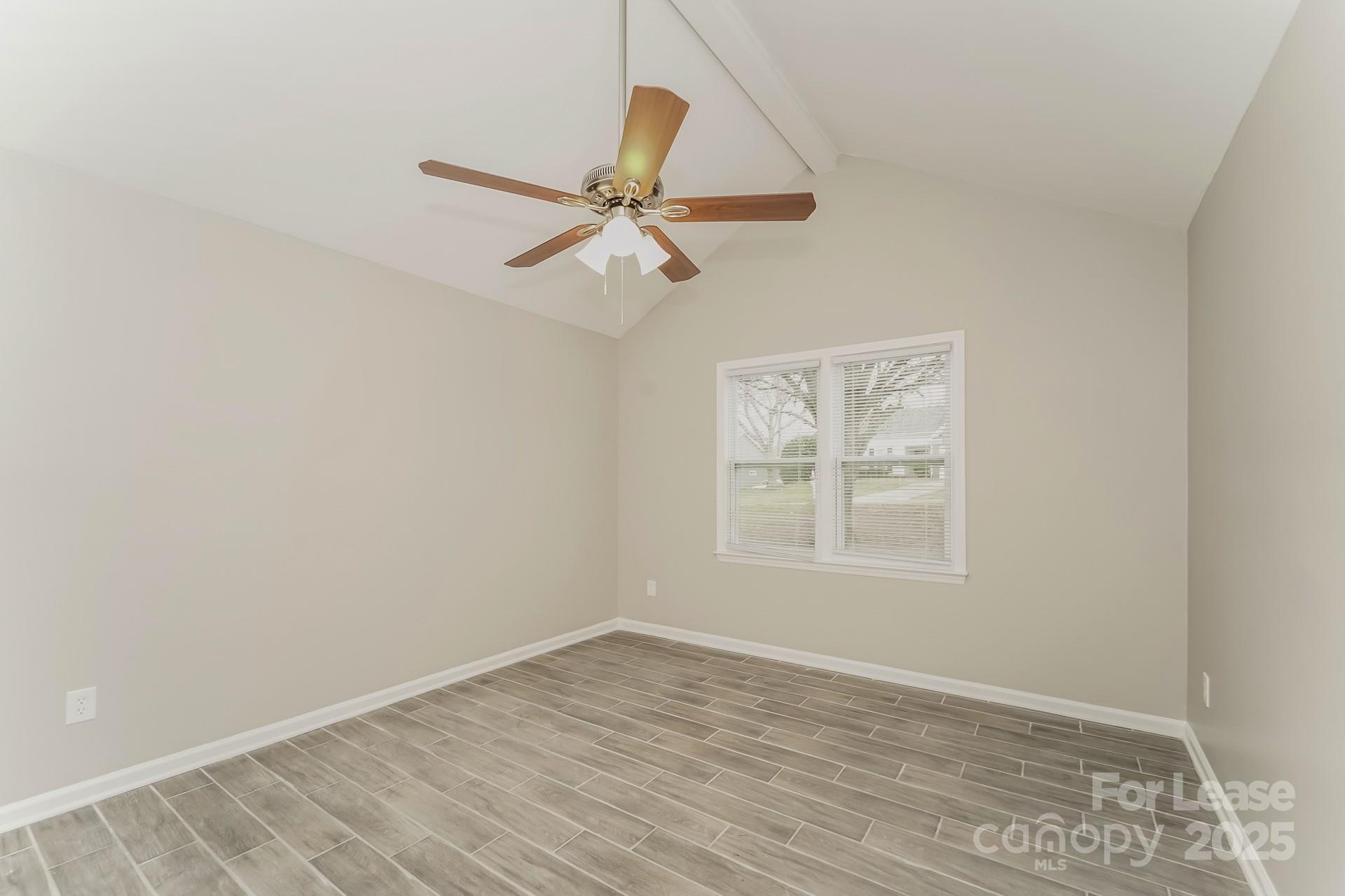 8301 Rocester Drive Charlotte, NC 28215 - Photo 9 of 16 an empty room with wooden floor fan and windows