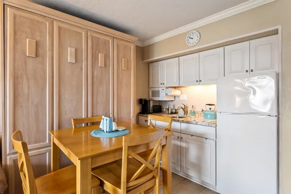 a kitchen with a refrigerator a stove a sink and white cabinets with wooden floor