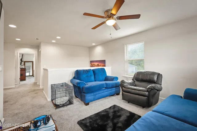 a living room with furniture ceiling fan and a window