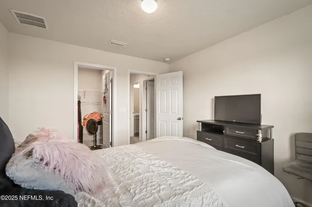 a bedroom with a bed and a flat tv screen on dresser