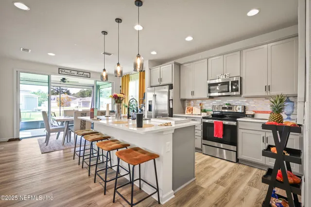 a kitchen with stainless steel appliances granite countertop a stove top oven a sink a dining table and chairs with wooden floor