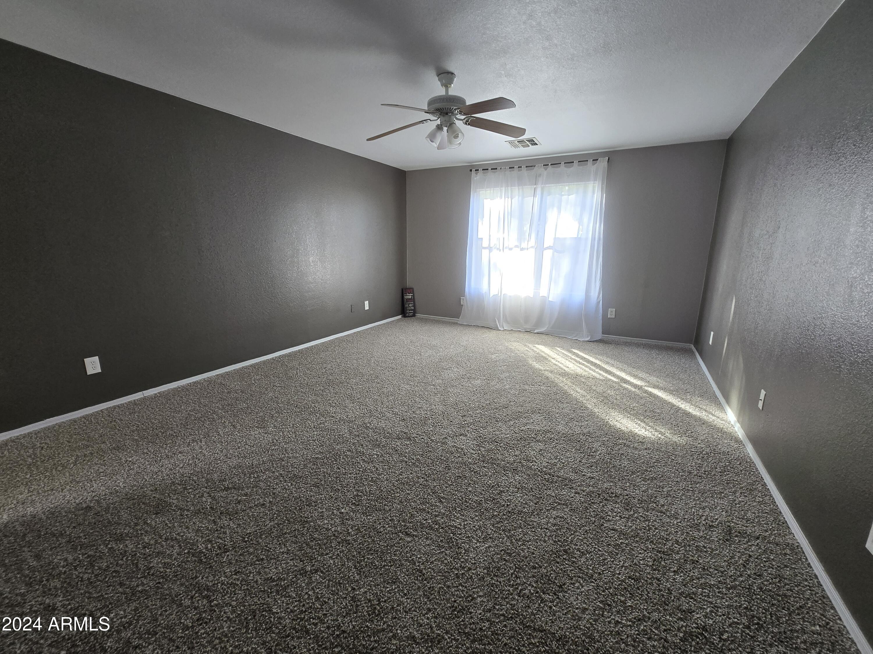 9365 West Eaton Road Phoenix, AZ 85037 - Photo 14 of 30 en empty room with windows and fan