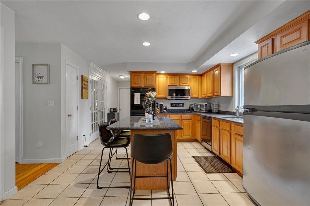 116 Meadow Street Carver, MA 02330 - Photo 8 of 42 a kitchen with stainless steel appliances granite countertop a refrigerator a sink a stove a dining table and chairs