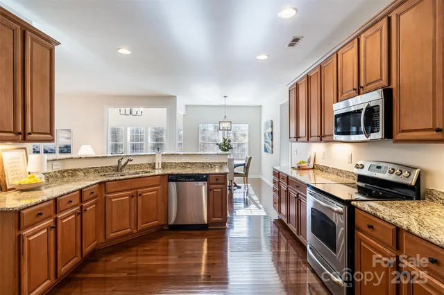 a large kitchen with stainless steel appliances granite countertop a stove a sink dishwasher and a microwave oven with wooden floor