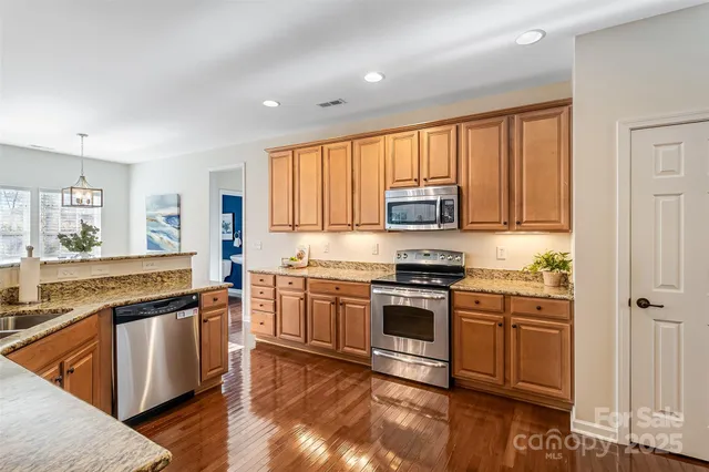 a kitchen with stainless steel appliances granite countertop a stove a sink and a refrigerator