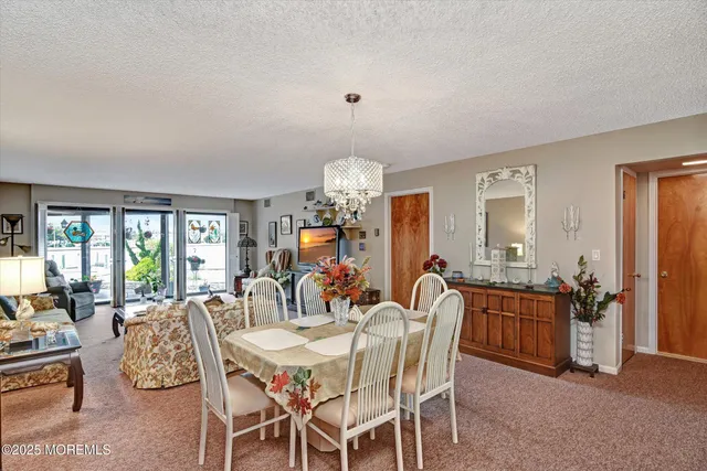 a view of a dining room with furniture a chandelier and a window