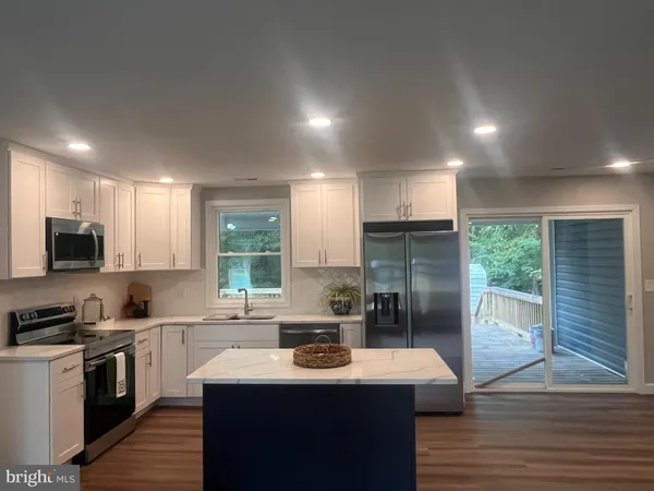 a kitchen with kitchen island granite countertop a sink stainless steel appliances and cabinets