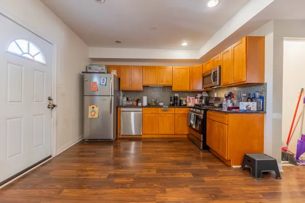 a kitchen with stainless steel appliances granite countertop a refrigerator a sink dishwasher and a stove with wooden floor