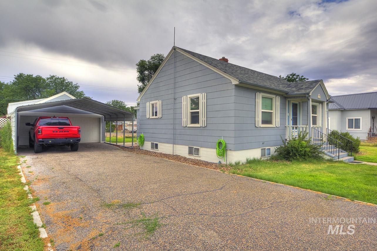 351 West Main Street South Vale, OR 97918 - Photo 31 of 33 Single-story residence featuring light blue siding, a covered front porch with railings, and a gravel driveway leading to an attached carport