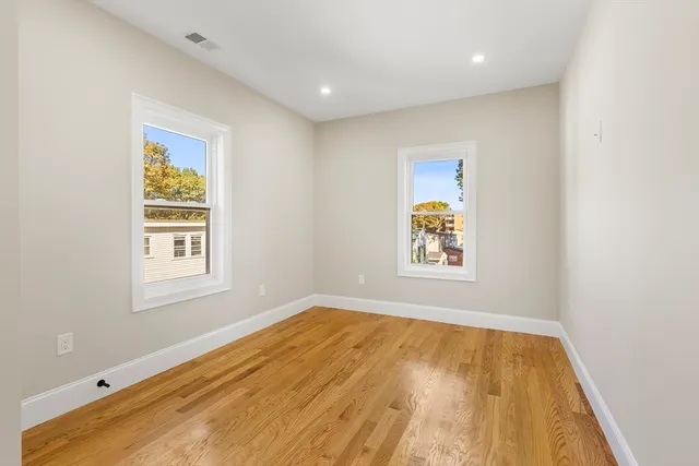 a view of an empty room with window and wooden floor