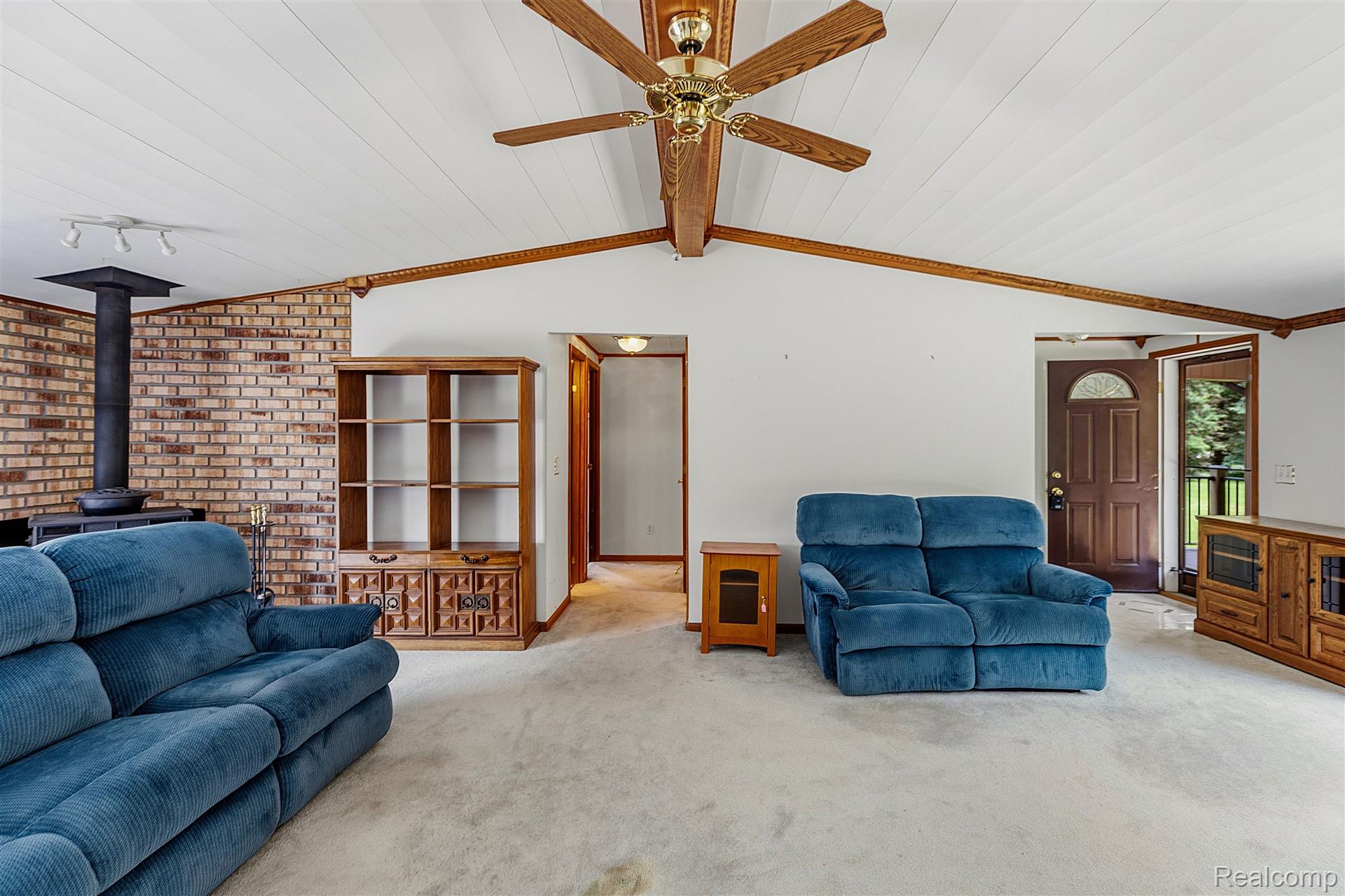 70919 Coon Creek Road Armada, MI 48005 - Photo 10 of 50 Carpeted living area with a wood stove, a wooden ceiling with exposed beams, track lighting, ornamental molding, and a ceiling fan