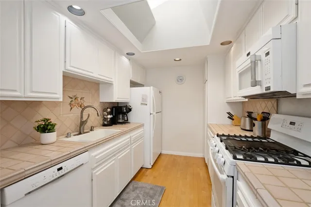 a kitchen with stainless steel appliances a stove a sink and white cabinets