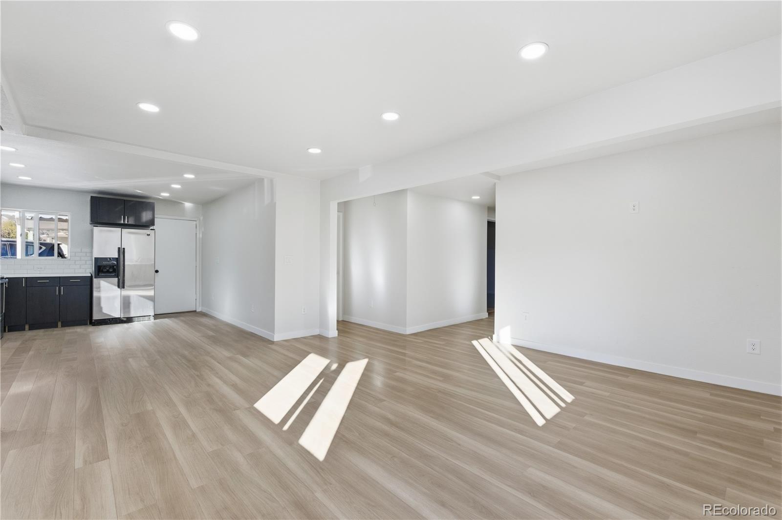 1550 South Xavier Street Denver, CO 80219 - Photo 4 of 46 a view of an empty room with wooden floor and a kitchen