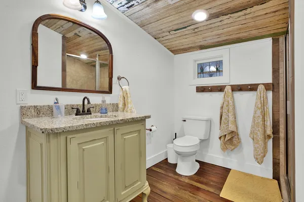 a bathroom with a granite countertop sink toilet and a mirror