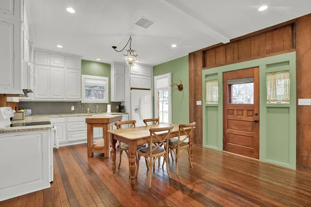 an open kitchen with wooden floor and stainless steel appliances