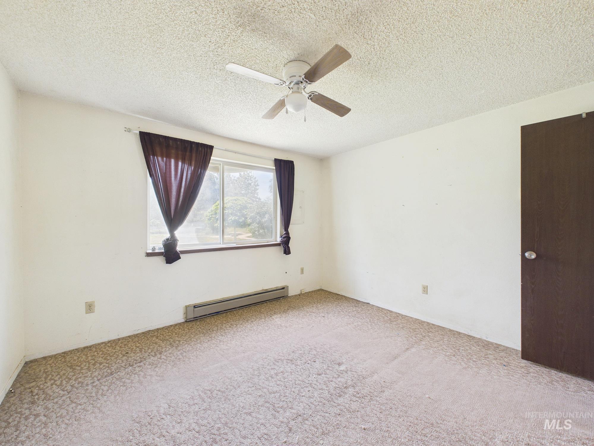 1527 North Plaza Road Emmett, ID 83617 - Photo 22 of 33 Room featuring a window, textured ceiling, ceiling fan with light fixture, and carpeted flooring