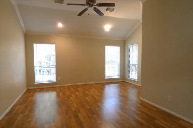 a view of an empty room with a window and wooden floor