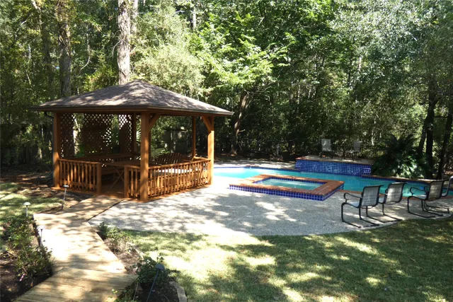 a view of swimming pool with lawn chairs under an umbrella