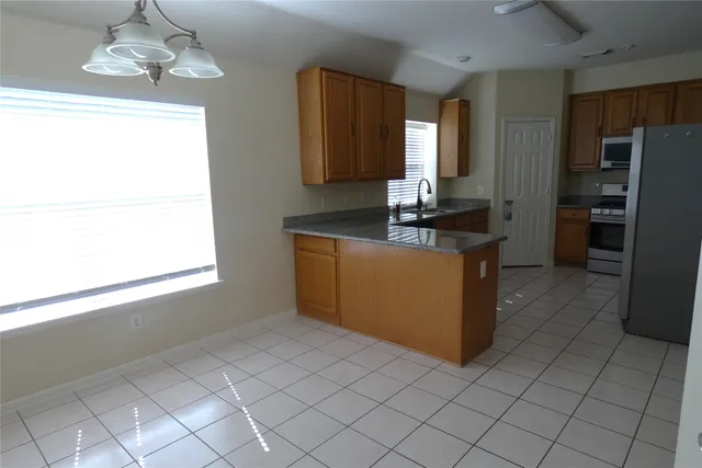 a kitchen with kitchen island granite countertop a sink cabinets and window