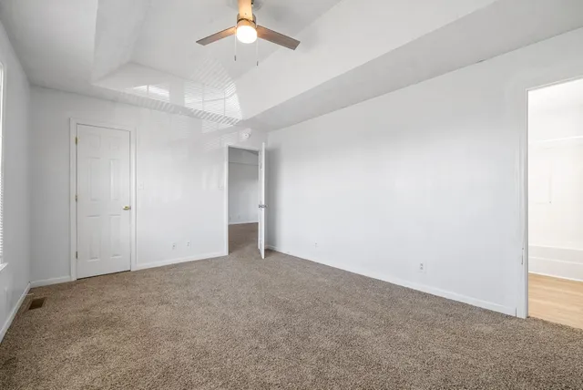 an empty room with a ceiling fan and a window