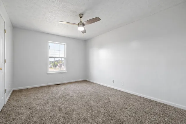 an empty room with a window and ceiling fan