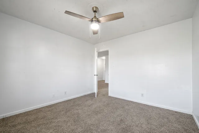 an empty room with closet and a ceiling fan