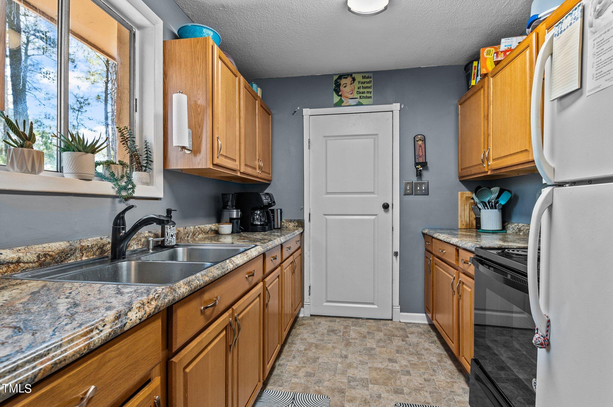 1708 Tee Dee Street Raleigh, NC 27610 - Photo 7 of 16 a kitchen with granite countertop a sink a stove and a refrigerator