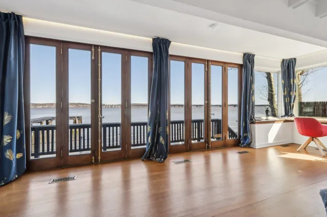 a view of an empty room with wooden floor and a floor to ceiling window