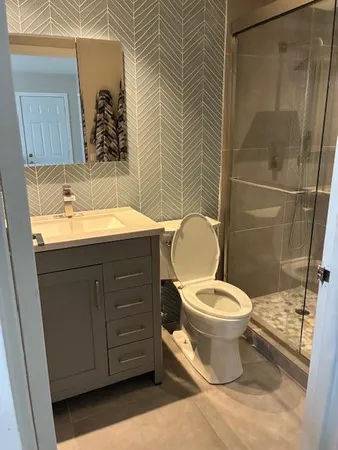 a bathroom with a granite countertop toilet sink and mirror
