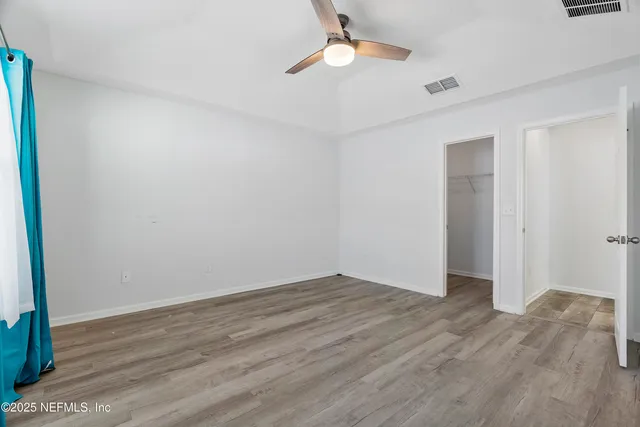 an empty room with wooden floor fan and window