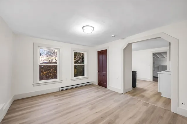 a view of empty room with wooden floor and windows