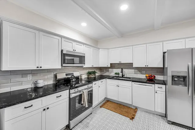 a kitchen with stainless steel appliances a sink stove refrigerator and cabinets