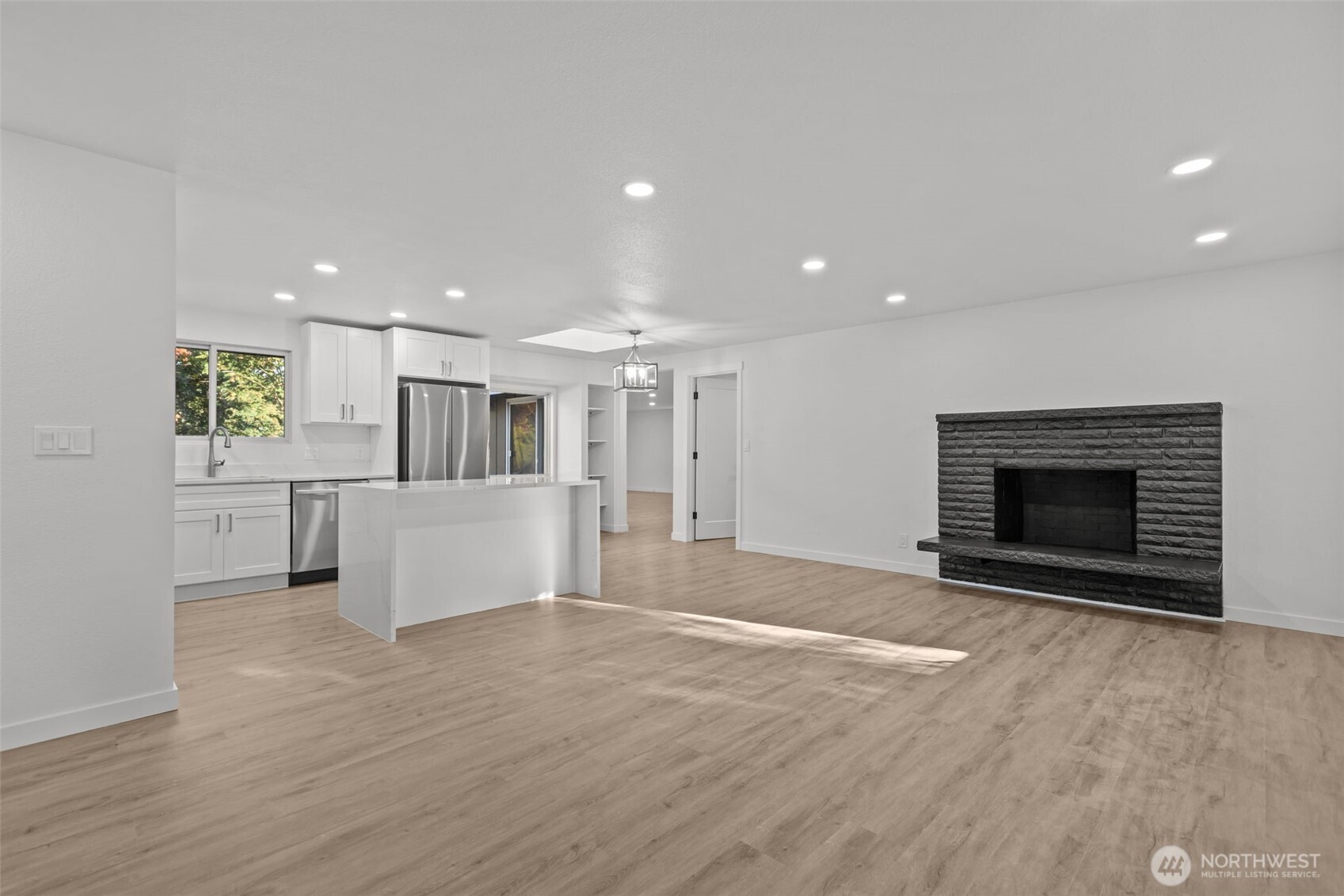 21316 188th Avenue Southeast Renton, WA 98058 - Photo 35 of 40 a view of kitchen and empty room with wooden floor and fireplace