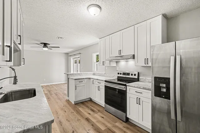 a kitchen with granite countertop a sink stove and refrigerator