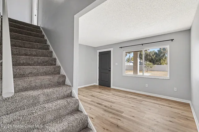 a view of an empty room with wooden floor and windows