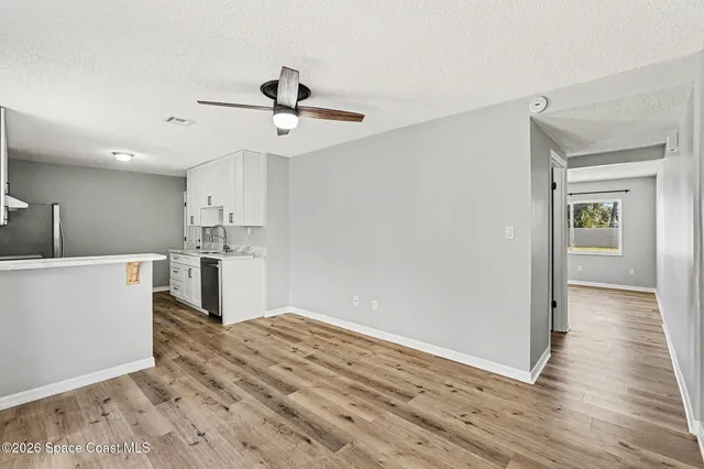 a view of kitchen and empty room with wooden floor