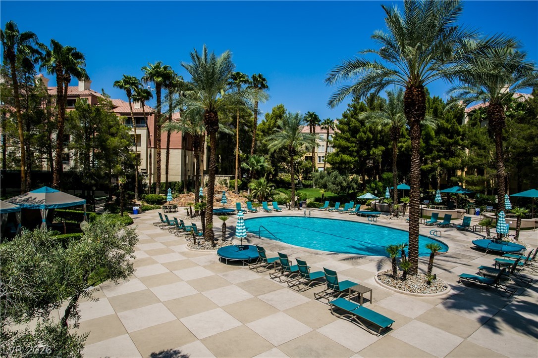230 East Flamingo Road, Unit 122 Las Vegas, NV 89169 - Photo 3 of 7 An inviting community pool with ample lounge seating awaits amidst swaying palm trees and lush greenery.