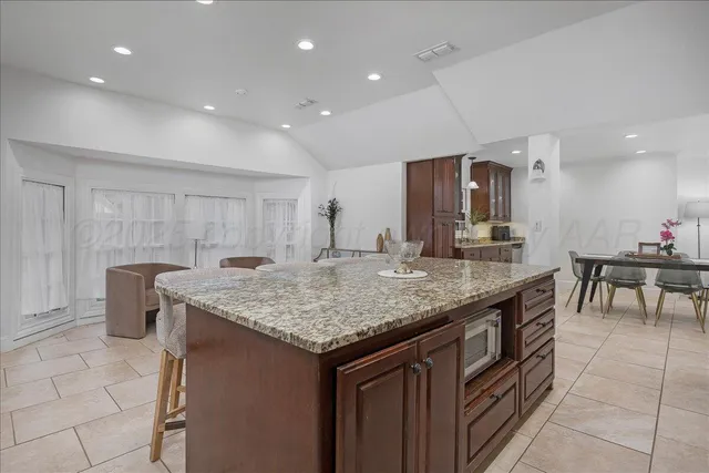 a kitchen with stainless steel appliances granite countertop a sink a stove a dining table and chairs