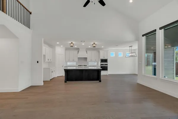a large white kitchen with kitchen island a refrigerator a sink dishwasher with a fireplace and cabinets