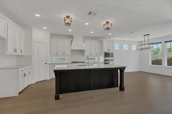 a kitchen with stainless steel appliances granite countertop a sink dishwasher a stove and a refrigerator with wooden floor