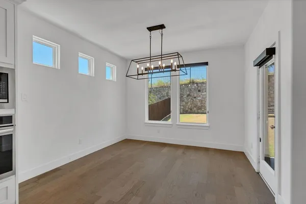 an empty room with wooden floor a flat screen tv and a chandelier