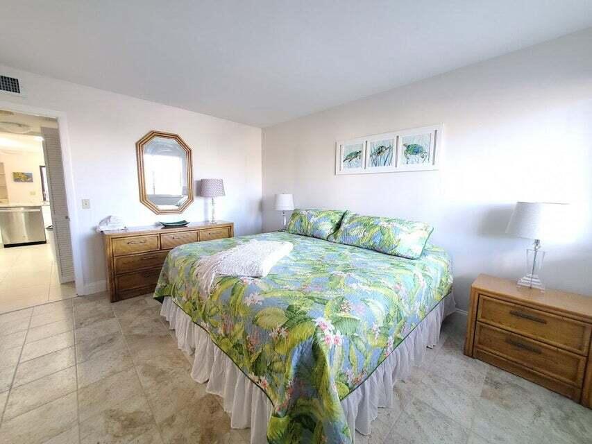 1605 Highway 1, Unit F203 Jupiter, FL 33477 - Photo 26 of 39 a bedroom with a bed and a chandelier