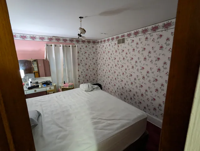 a bed sitting in a spacious bedroom next to a window