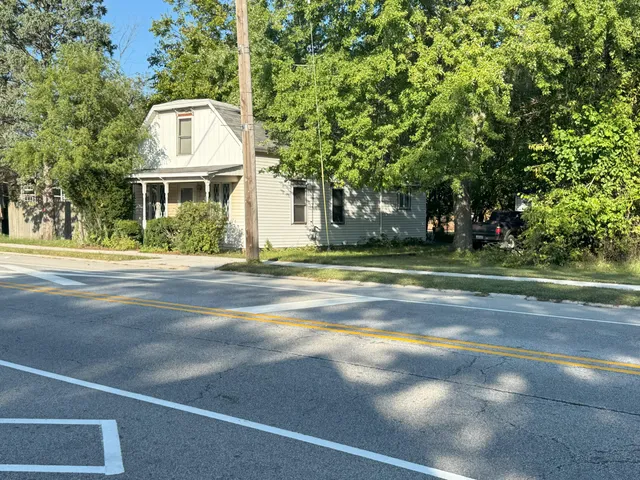 a view of a big house with a big yard plants and large trees