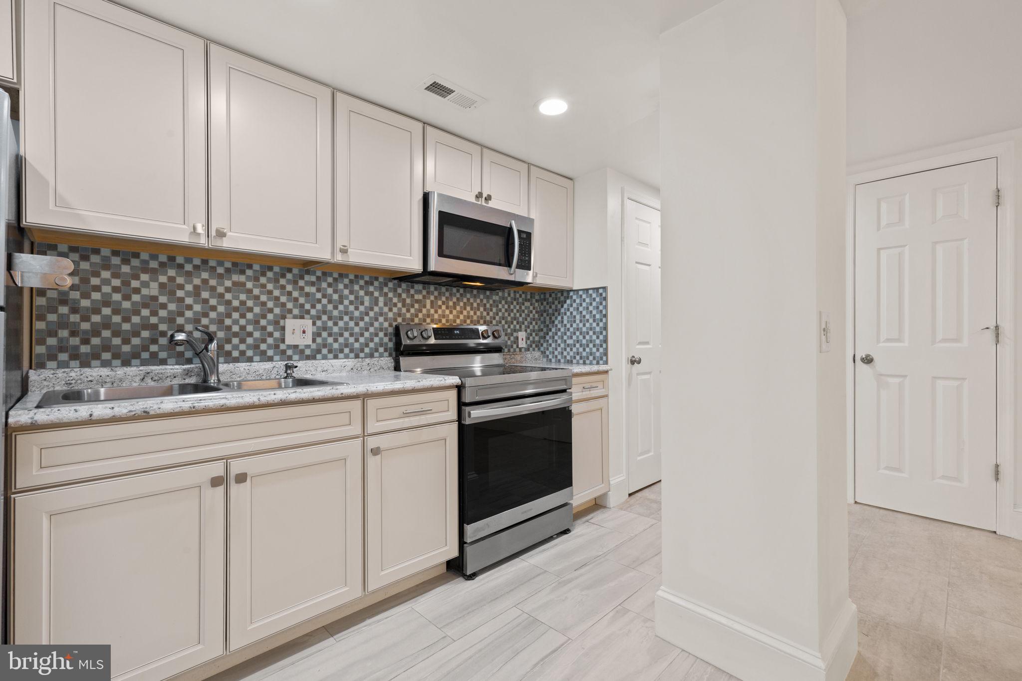 1308 Park Road Northwest, Unit 2 Washington, DC 20010 - Photo 5 of 17 a kitchen with white cabinets stainless steel appliances and sink