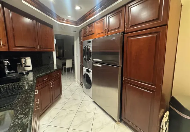 a kitchen with granite countertop stainless steel appliances a refrigerator a stove top oven and cabinets