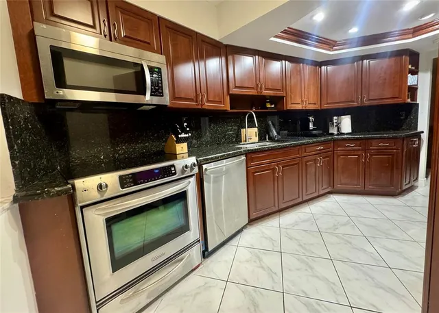 a kitchen with granite countertop a stove microwave and cabinets