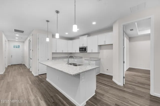 a kitchen with stainless steel appliances granite countertop a sink window and white cabinets