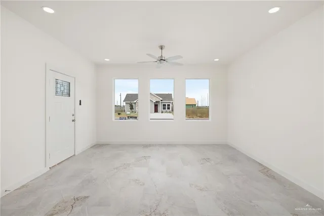 an empty room with chandelier fan and windows