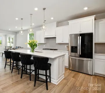 a kitchen with stainless steel appliances kitchen island granite countertop a table chairs and a refrigerator